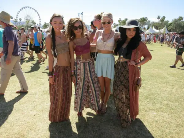 Cztery młode kobiety w letnich strojach pozują na tle festiwalu Coachella.