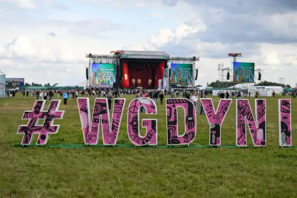 Różowe litery #WGDYNI na trawie przed sceną festiwalową Open'er.