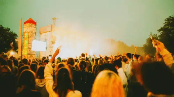 Tłum ludzi na koncercie, uniesione ręce, scena z oświetleniem. Tak wyglądają juwenalia, czyli święto studentów.