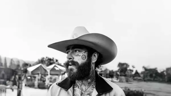 Post Malone w kowbojskim kapeluszu, z tatuażami na twarzy, gotowy na swój kolejny koncert.