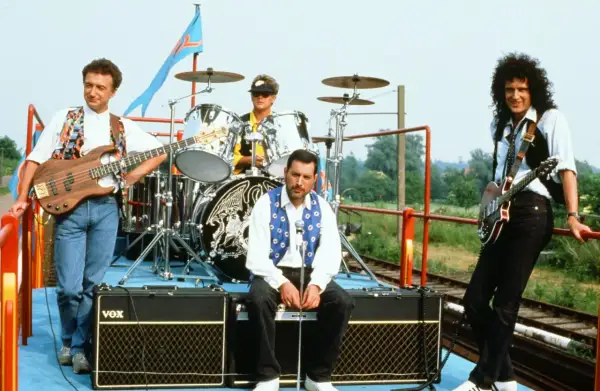 Zespół Queen na wagonie kolejowym, gotowy do niezapomnianych koncertów. Freddie Mercury, Brian May, John Deacon i Roger Taylor.