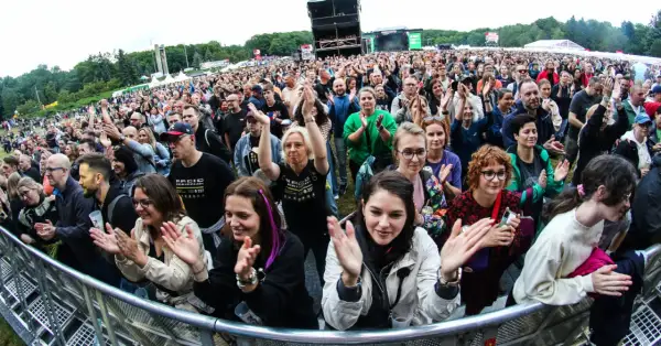 Tłum na koncercie w Poznaniu, fani klaszczą i cieszą się występem. Widoczny fragment sceny i festiwalowej atmosfery.