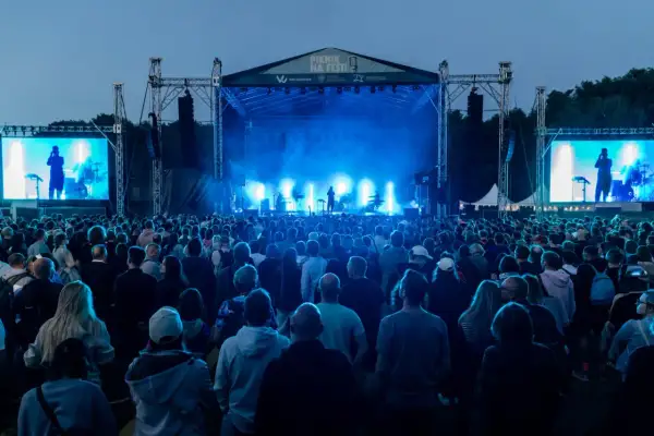 Koncert na festiwalu w Cytadeli, tłum ludzi przed sceną oświetloną niebieskim światłem.