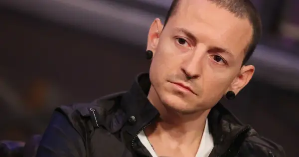 Chester Bennington z Linkin Park, z charakterystycznymi czarnymi tunelami w uszach, w czarnej kurtce.