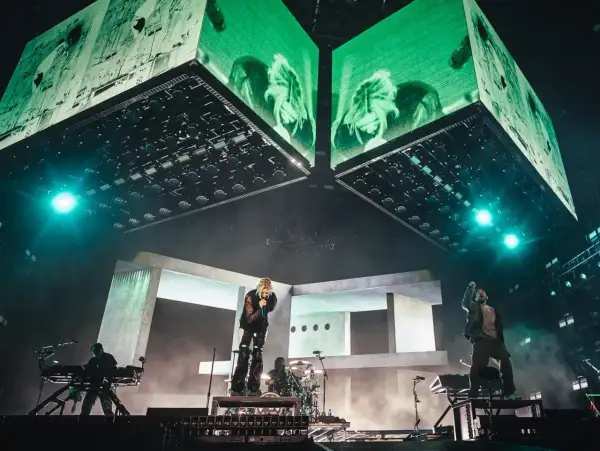 Energetyczny linkin park opener na scenie. Wokalista śpiewa, zespół gra, a nad nimi ogromne ekrany z zielonymi wizualizacjami.