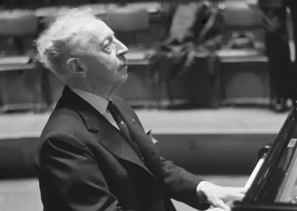 Artysta w garniturze, polski pianista jazzowy, pochyla się nad fortepianem, skupiony na grze.