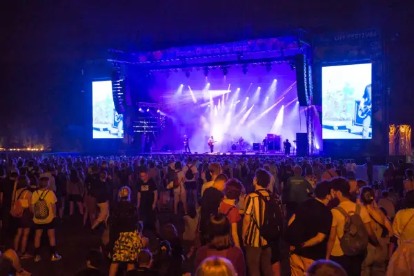 Tłum ludzi na OFF Festivalu, podziwiający koncert na oświetlonej scenie.